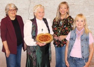 Lilac Festival and Boots on the Boulevard event organizers: Anita Miller Program Manager, Claremore Main Street; Susan Gebhart, Three-Twenty on Main Event Center; and Brenda Reno, Sailer Antiques & Collectibles with local celebrity Ollie Starr who will lead the Old Fashioned Pie Auction as “Aunt Eller” on May 22 at 6:45 pm. Value News VN Magazine and Values, Inc. photo, May 2026.