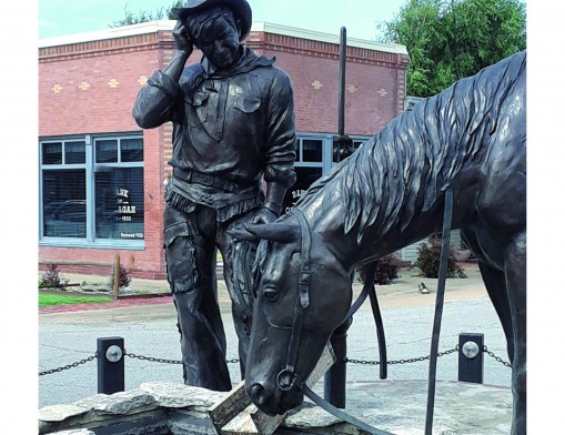 “The Cherokee Kid” statue created by Sandra Van Zandt in 1995. The restored Bank of Oolagah is in the background.