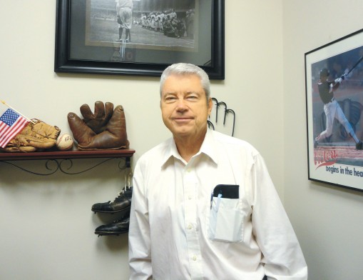 Real estate broker (and sports fan) Fred Keas stands by the baseball memorabilia in his Bixby office.