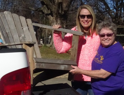 Auction committee members, Mendy Stone (left) and Darlene Armstrong unload the Adirondack chair they picked up in a Claremore alley.  It will be refurbished and artistically painted for the “Chair-ity” Auction by Barbie Rodriquez.