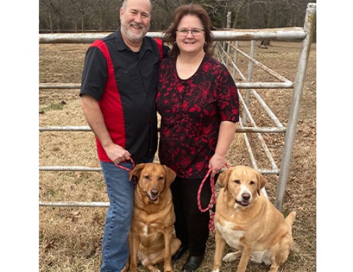Brant and Angela stand on their Coweta property with two of their five dogs.