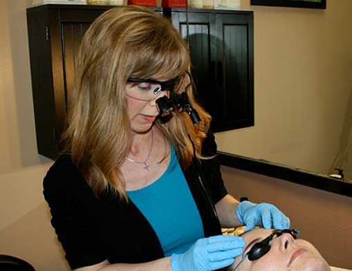 Nicole McGinnis, licensed aesthetician and owner of Reveal Salon, at work on acne treatment.