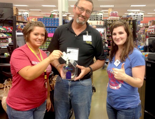 Harp’s Foods of Inola Manager, Mark Dill, and employees display one of the Round Up houses placed in support of Safenet Services.