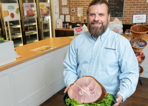 Lee Griffin, owner of Tulsa’s Honey Baked Ham store, with a spiral-cut bone-in half halm.