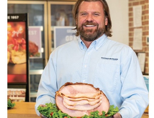 Lee Griffin, owner of Tulsa’s Honey Baked Ham store, with a spiral-cut bone-in half halm.