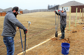 Advantage employees Blake and Scott digging post holes to be used to hold posts to support a fence at a residence in Claremore.