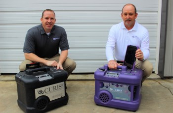 Chris Schultheis and Chuck Peeples display two of the CURIS system units used to disinfect and decontaminate homes, offices, schools, nursing homes, churches, and more.