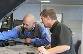 David Thompson, service director, and David Reed, service advisor, are inspecting a noise under the hood for a customer.