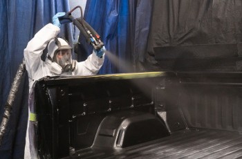 Justin Cook professionally applies a protective bed liner to a custom Chevrolet Silverado.