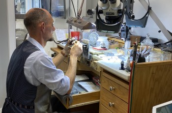 Casey Kelly carefully examines a piece of jewelry that has been brought in to be repaired.