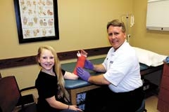 Dr. Bradley Lawson casts a young patient’s arm in the casting room at the Central States Orthopedics Owasso location.