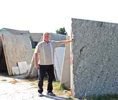 Rex Marsh, owner of Harmony Star Marble &amp; Granite, stands beside a display of granite to be turned into a beautiful countertop for someone’s kitchen or bathroom.