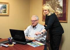 Kathy Geyer, sales associate, and Allen Stout, broker/owner of OklaHomes Realty, Inc., look over a recent listing on their website. Stout’s company is celebrating 25 years in the real estate business.