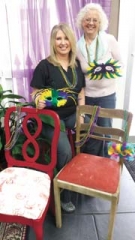 Downtown Claremore businesses including Waterfront Frame &amp; Art and Vintique Charm will be represented at the Mardi Gras themed “Chair-ity” Auction benefiting Volunteers for Youth on February 17. Displaying how the old can 
become new are Waterfront co-owner Linda McFall(standing behind an untouched chair) and Vintique Charm’s 
representative Carla Reynolds (seated behind a re-purposed, Paris themed chair).