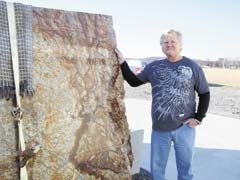 Rex Marsh, owner of Harmony Star Marble, stands next to a piece of high-quality granite.