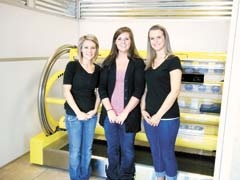 Touch of Sun Owasso manager Megan Shelton with employees Brittany and Whitney in front of the Ultra High UV Scan machine.