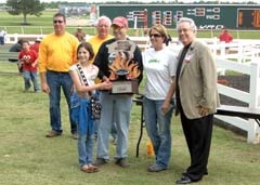 A recognized Kansas City Barbecue Society champion, Little Pig Town, was the 2011 Reveille Rotary Boots & BBQ Festival Champion. Scot Kee, his wife Rocky, and daughter Bailey, ­receiving last year’s trophy in the Will Rogers Downs Winners’ Circle. Joining the Little Pig Town team were event organizers: Reveille Rotarians John Walke, Club President Roger Fleming, both left, along with Cherokee Nation Enterprises General Manager Tony Cavallo.