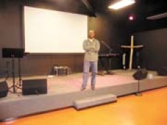 Pastor Alvin Fruga stands on the stage at the new location of Presence Theater Church at 76th Street North and 129th East Avenue.