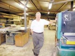 Bill Jack, owner of Brunson Cabinet Company, stands next to a wide belt sander in his shop.