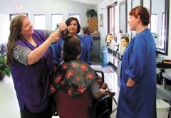Claremore Beauty College instructor Mindy Gerving demonstrates a haircutting technique to students Angie and Lupe.