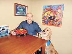 Hebert’s owner Ed Richard tempts Casey, a Therapetics service dog trainee, with a sampling of authentic Cajun crawfish featured during Crawfish Festival 2011.