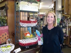 Employee Mary Kate Bollman shows off a display of kitchen items, including Eucalyptus Stoneware, available at J&amp;J Pharmacy in Claremore.