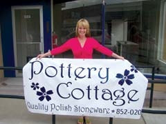 Leslie Cohen holds the banner in front of her new location at the corner of Cherokee and Will Rogers in historic downtown Claremore.