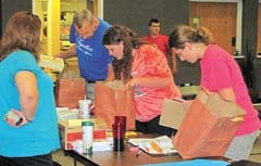 Volunteers prepare school supply bags for those in need. Ray Dawson, program administrator, is pictured in the blue T-shirt. “All funds donated go directly to the purchase of supplies with the program being administered completely by volunteers,” he says.