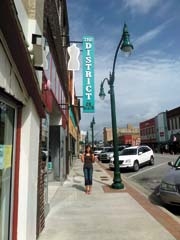 Madison Todd under the new sign at The District on Main.