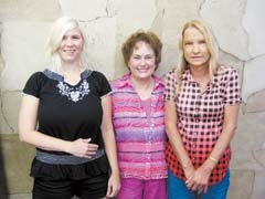 Laurann Farris (center) of the Broken Arrow Main Street Merchants Association and vendors Jessica Robinson and Shelly Johnson in front of a faux leather wall at Your Design.