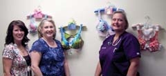 Boobdazzled Brassiere committee members Cheryl West and Peggy Trease admire a few of the bra art displayed at Dr. Melinda Steelmon’s OB/GYN office. Dr. Steelmon purchased several of the bras at the last bra art auction.