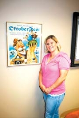 Tulsa Oktoberfest Executive Director Amber Hinkle ­displays a festive poster from an earlier event.