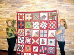Fern Patterson, quilt maker, and Sharon Pettit, event ­­
co-chair, hold the “Country Sampler” quilt that will be ­raffled at the Quilt Show.