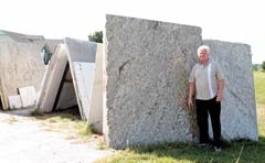 Rex Marsh, owner of Harmony Star Marble &amp; Granite, stands beside a display of granite that will be turned into a beautiful countertop for someone’s kitchen or bathroom.