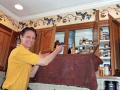 Tracy Booth points out a fully loaded kitchen cabinet that is undergoing the Gleam Guard Dustfree Wood Refinishing process.