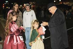 A magician at last year’s Dickens on the Boulevard­ mesmerizes a young girl as other participants watch his act.