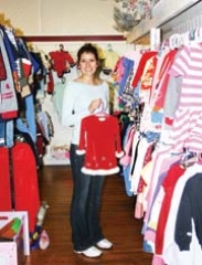 Part-time employee Kathy Clifton displays one of the quality child’s dresses available at Thrift Harbor.