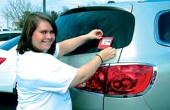 Megan Lopez, Claremore High School student, places a decal on a car window to encourage others to pledge never to ride with an impaired driver. Lopez, who has been a member of Students Against Drunk Driving (SADD) for three years, currently serves as secretary of the organization.