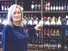 Melinda Kennedy, co-owner of Wine Down Spirits in Claremore, shows off some of the wines available for purchase, including several local varieties.